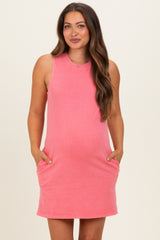 woman wearing a coral sleeveless maternity dress with pockets and showing her baby bump