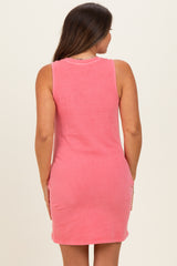 woman wearing a pink sleeveless maternity dress, showing a fitted style from the back