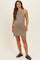 woman wearing a taupe sleeveless maternity dress with a fitted silhouette and standing in a neutral pose