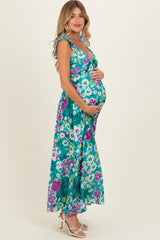 woman wearing a teal floral maternity maxi dress and holding her baby bump