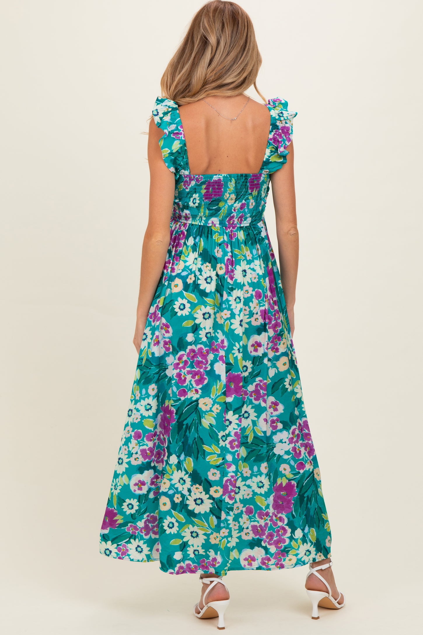 woman wearing a floral maternity maxi dress with ruffled straps and a fitted bodice, showing a baby bump from the back