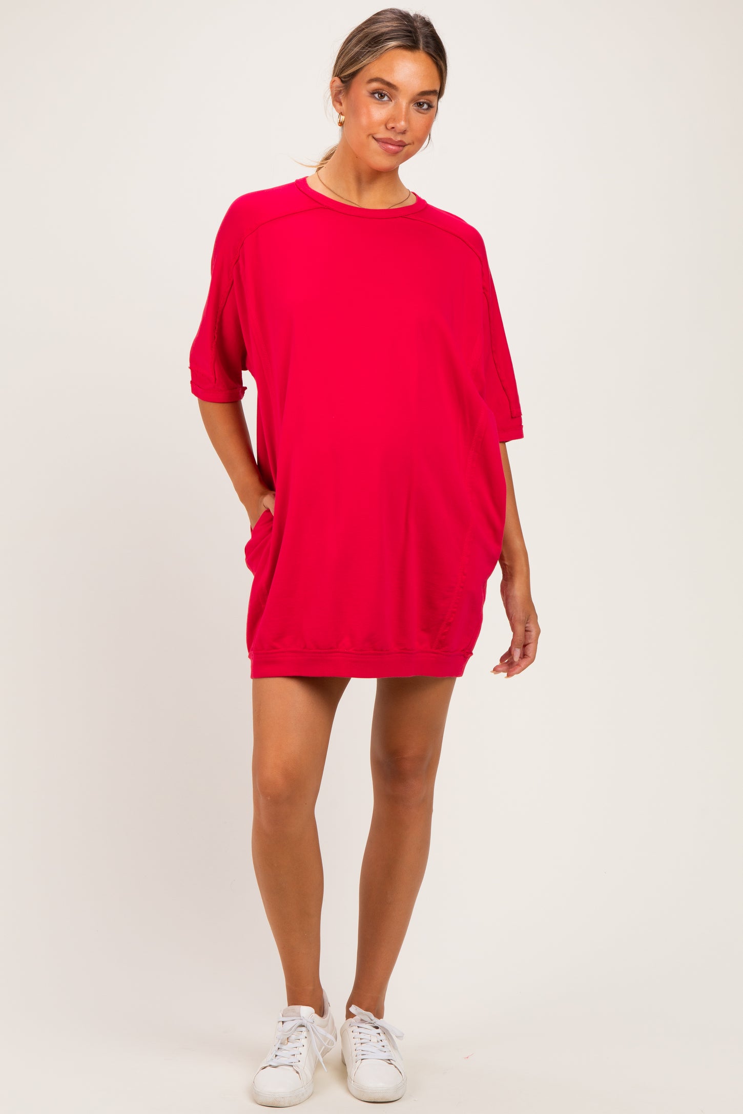 woman wearing a bright pink oversized maternity dress with short sleeves and side pockets
