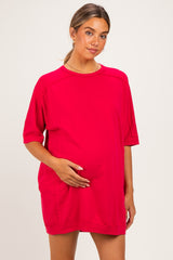 woman wearing a bright red oversized maternity dress and holding her baby bump