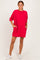 woman wearing a loose-fitting vibrant red short dress with pockets and three-quarter sleeves, paired with white sneakers
