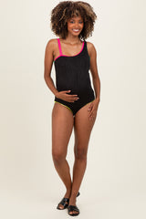 woman wearing a black maternity swimsuit with pink straps and yellow accents, showing her baby bump