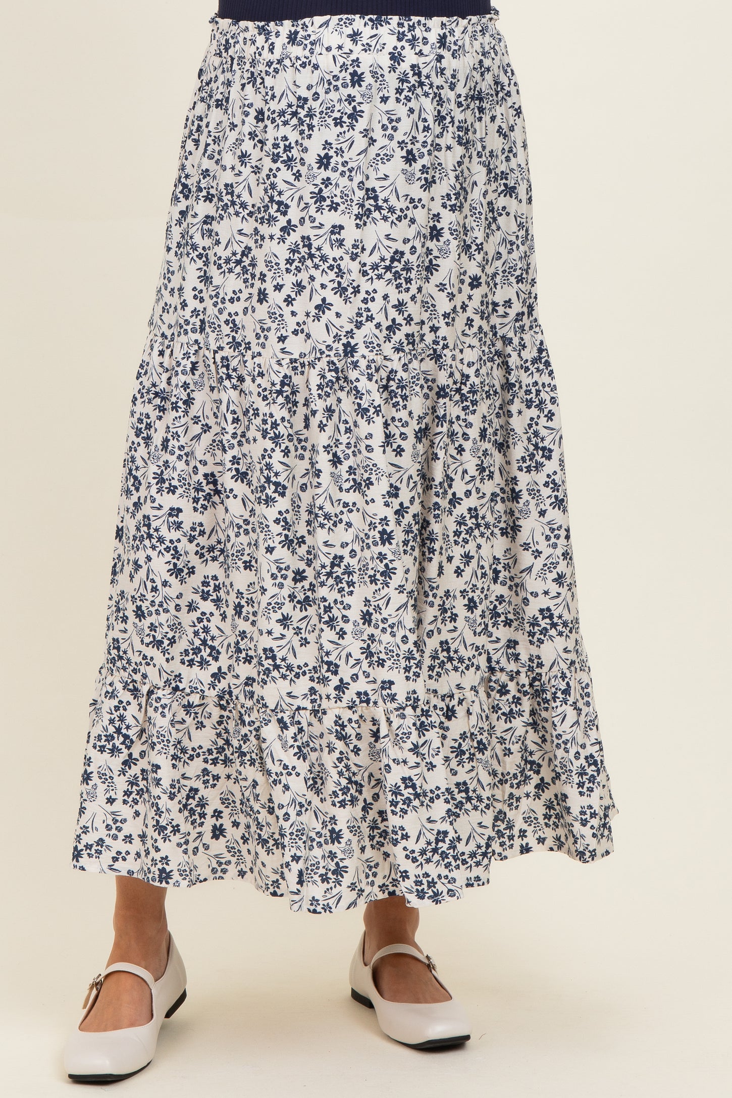 maternity wear floral maxi skirt in white and navy with tiered ruffles, model wearing white shoes with a flat heel