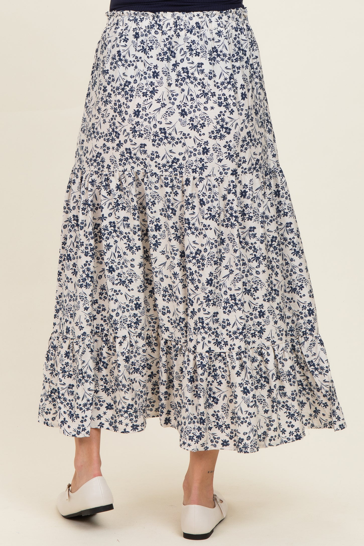 maternity wear tiered long floral skirt in white and navy with a flowy design, model shown from the back