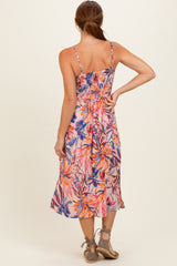 woman wearing a back view of a floral print smocked midi dress with adjustable straps and a flared skirt