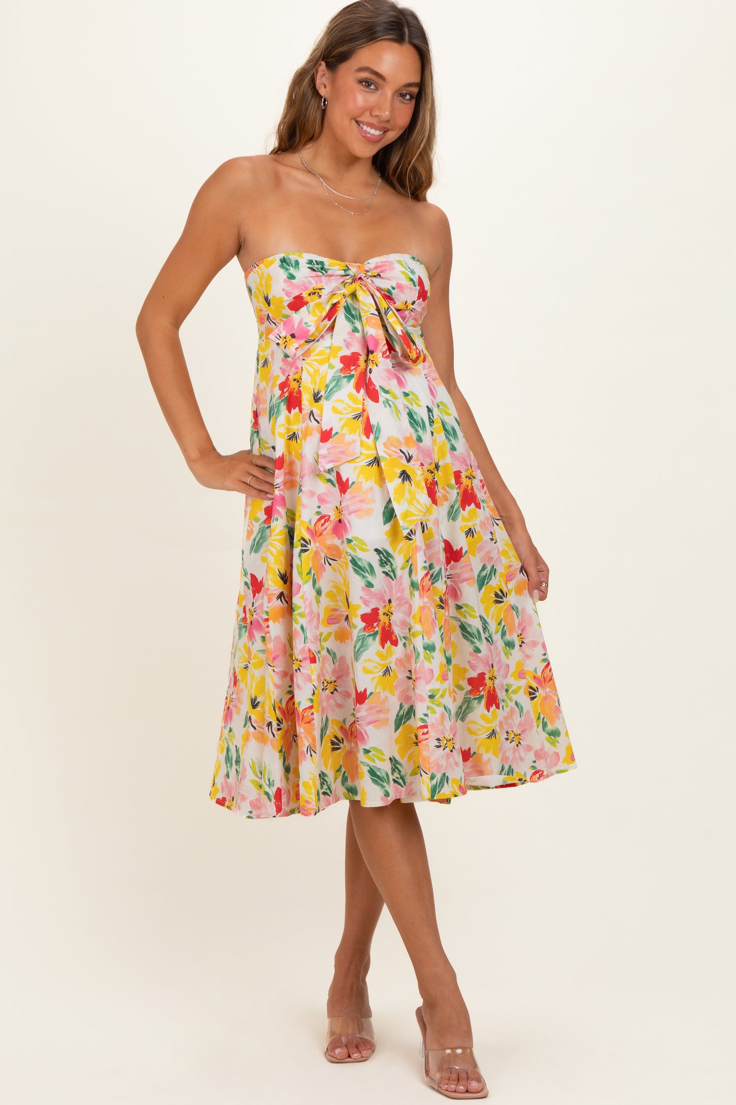 woman wearing a floral strapless maternity dress with a tie detail and a visible baby bump