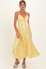 woman wearing a yellow floral maternity dress with a tie front and buttons, showcasing her baby bump