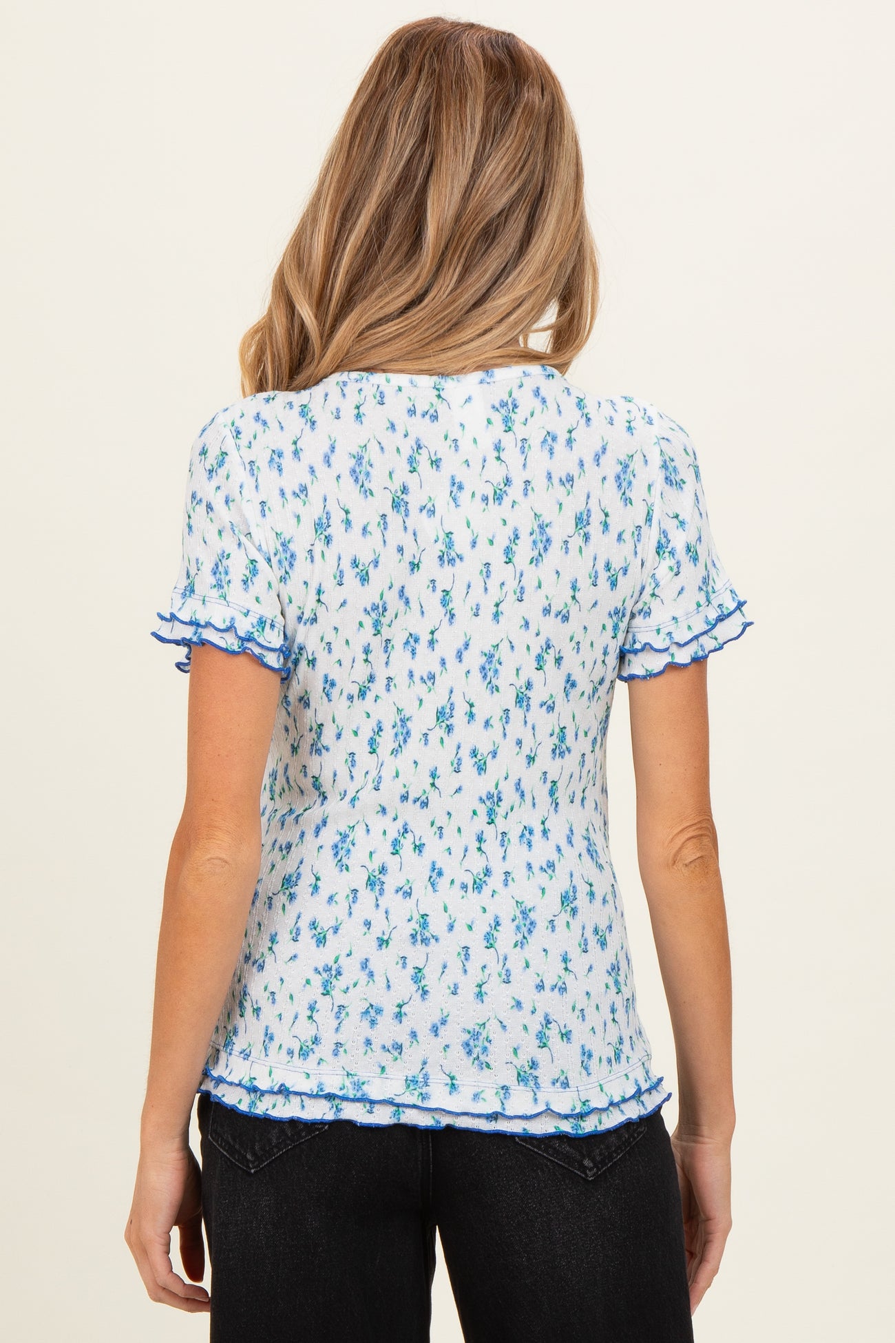 woman wearing a blue and white floral short sleeve maternity top with ruffled edges