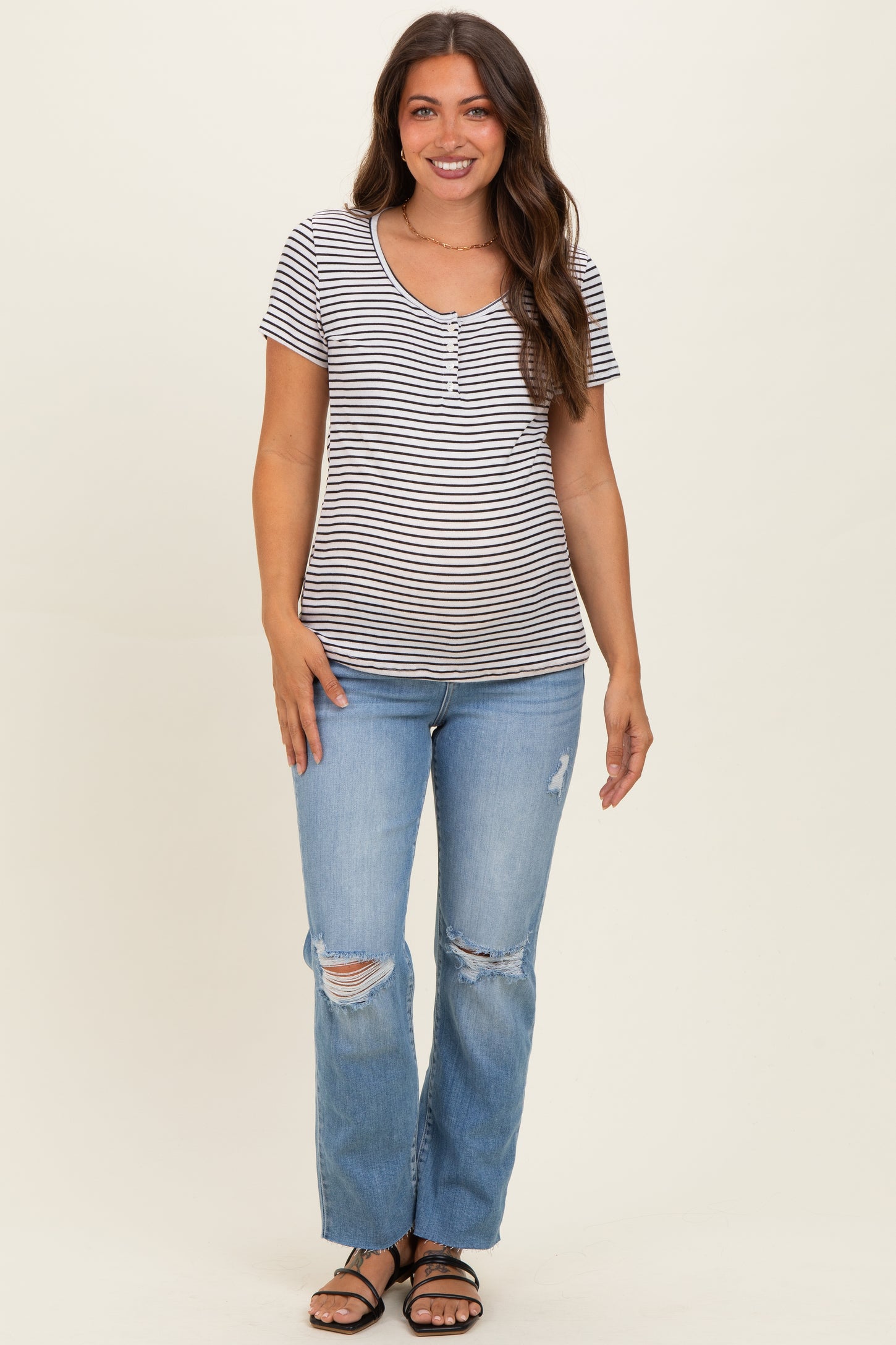 woman wearing a striped maternity t-shirt with short sleeves and paired with distressed light blue jeans