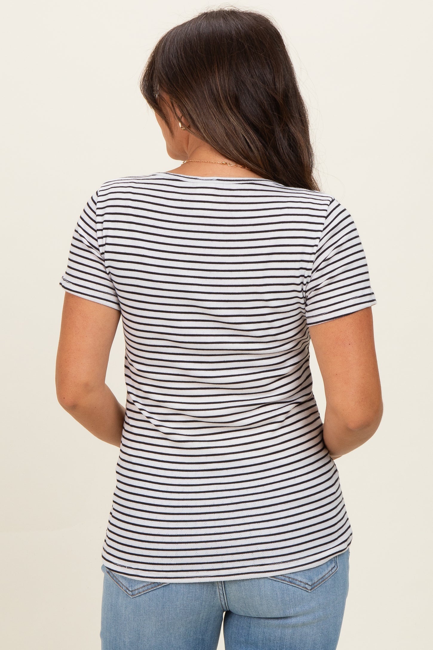 woman wearing a striped maternity short sleeve top, viewed from the back, paired with blue jeans