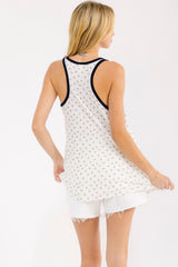 woman wearing a white tank top with a navy floral print and contrasting navy trim, shown from the back with white shorts