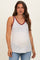 woman wearing a white maternity tank top with a floral print and burgundy trim, showing her baby bump