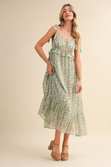 woman wearing a green and white floral maxi dress with adjustable straps and a ruffled hem