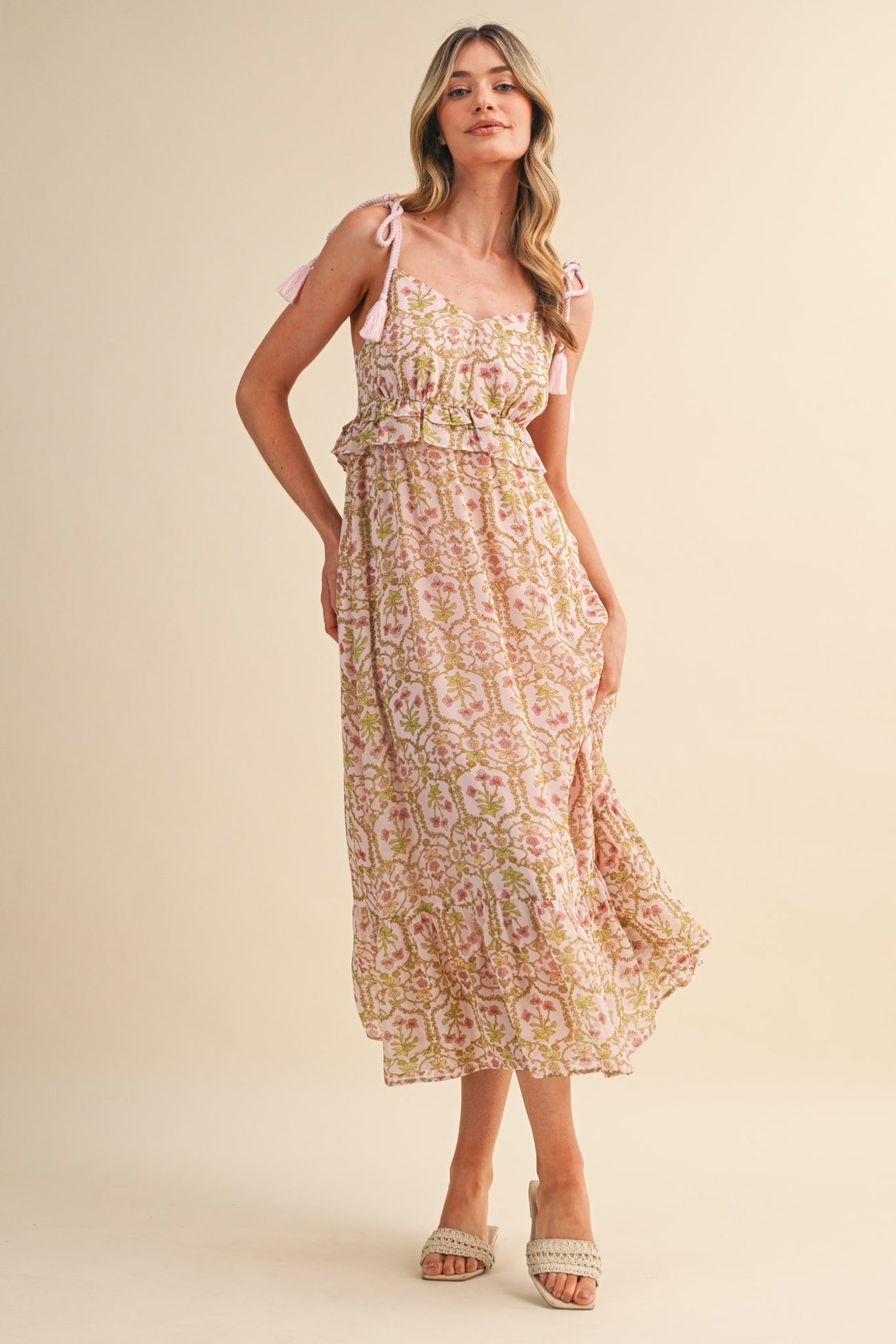 woman wearing a pink and green floral maxi dress with tie straps and a ruffled waist detail