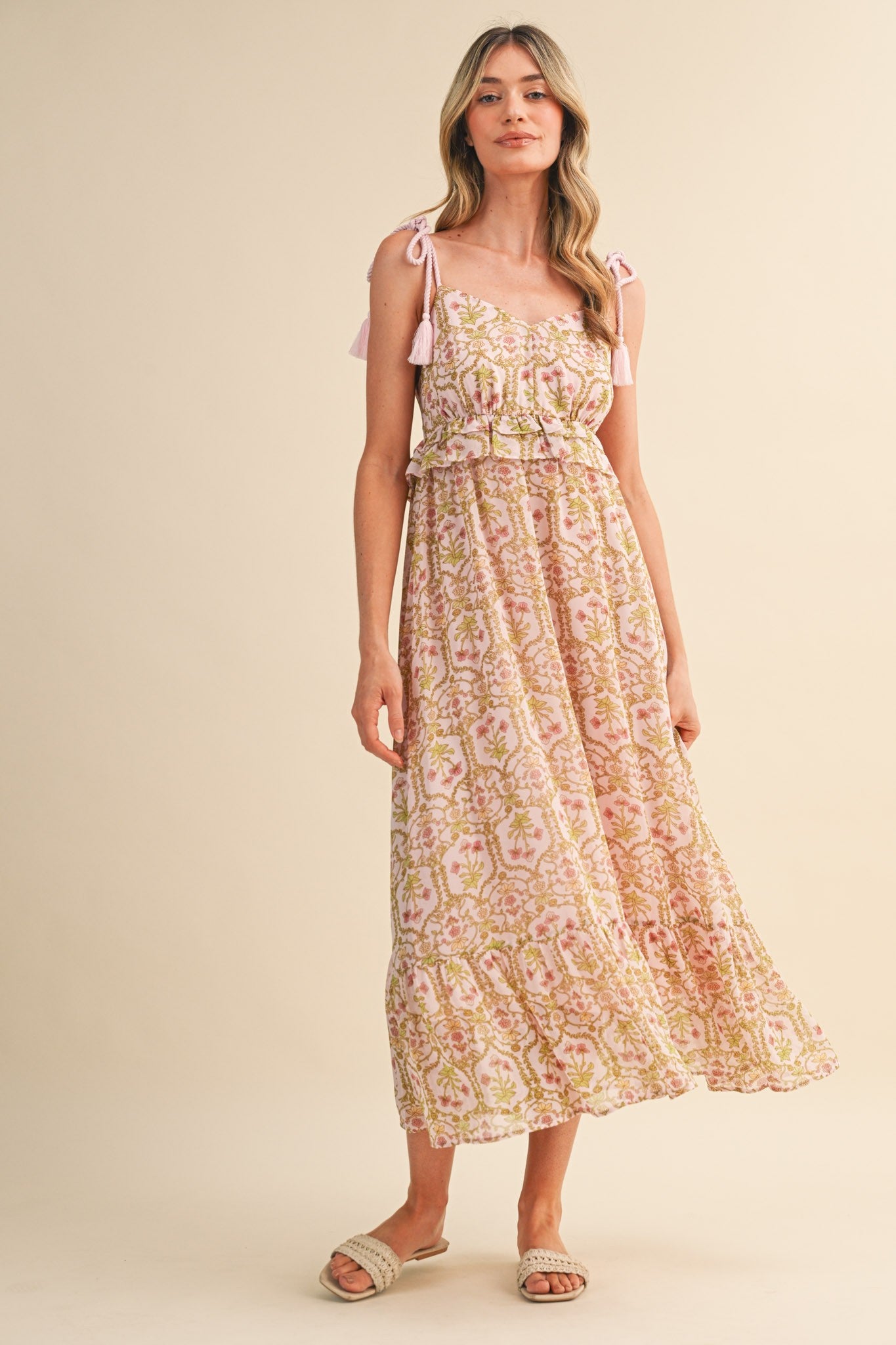 woman wearing a pink floral maxi dress with adjustable tie straps and a tiered skirt