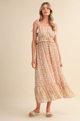 woman wearing a pink floral maxi dress with adjustable tie straps and a tiered skirt