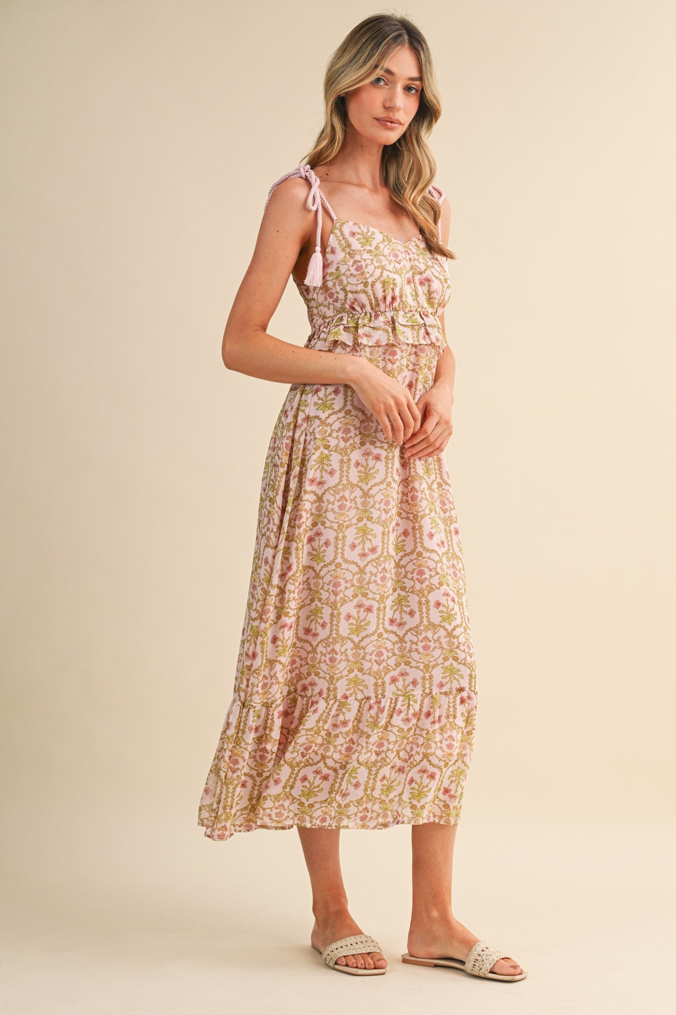woman wearing a pink and yellow floral maxi dress with adjustable straps and a ruffled hem