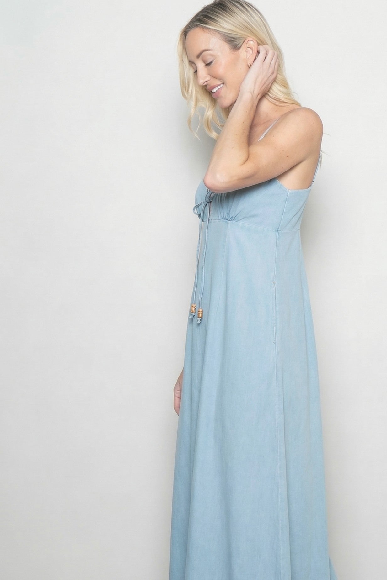 woman wearing a light blue maxi dress with adjustable straps and decorative beads