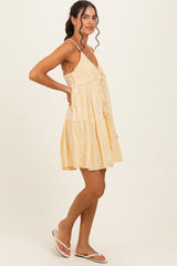 woman wearing a light yellow tiered sundress with lace detailing and spaghetti straps