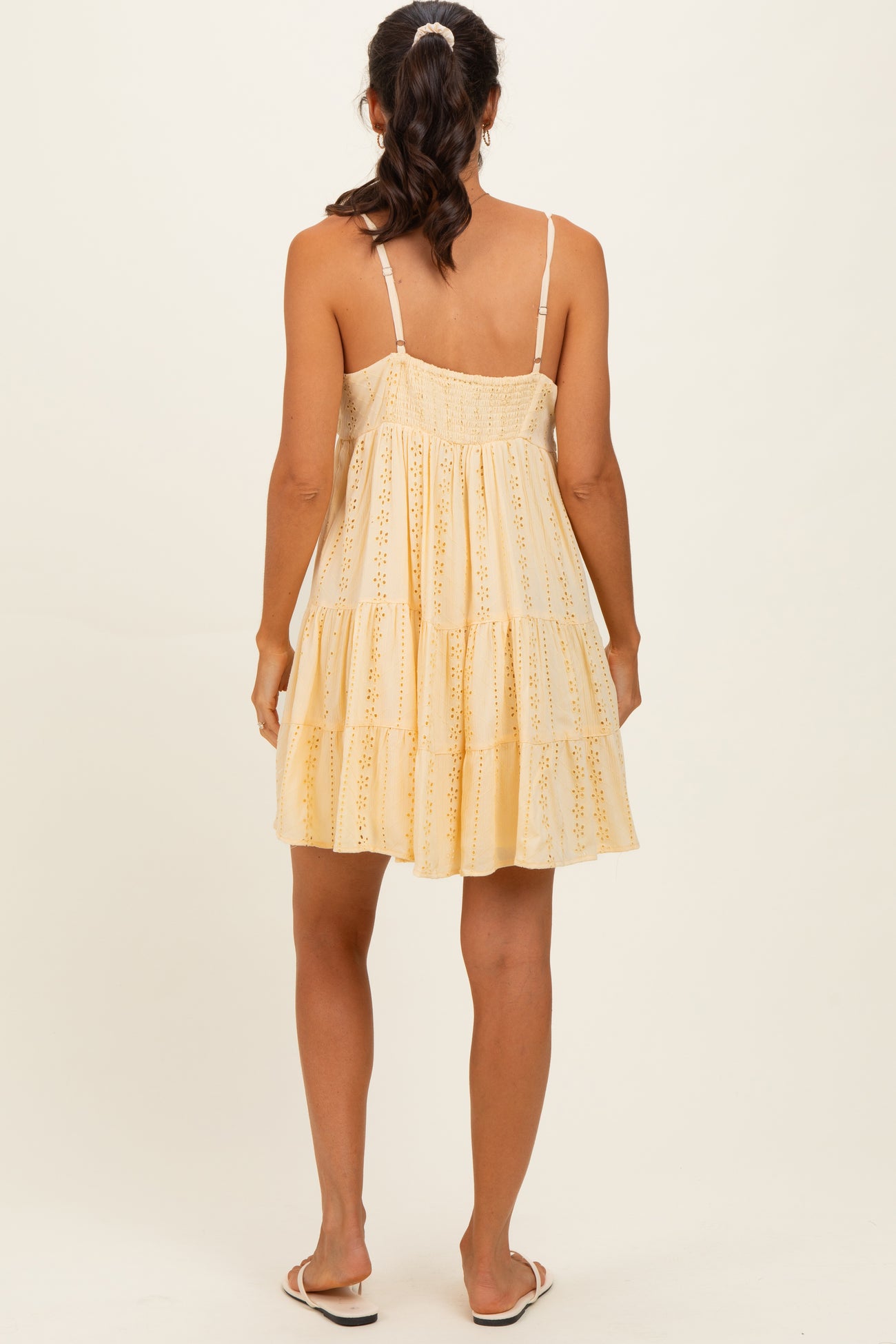 woman wearing a yellow tiered sundress with a strappy back and broderie anglaise details