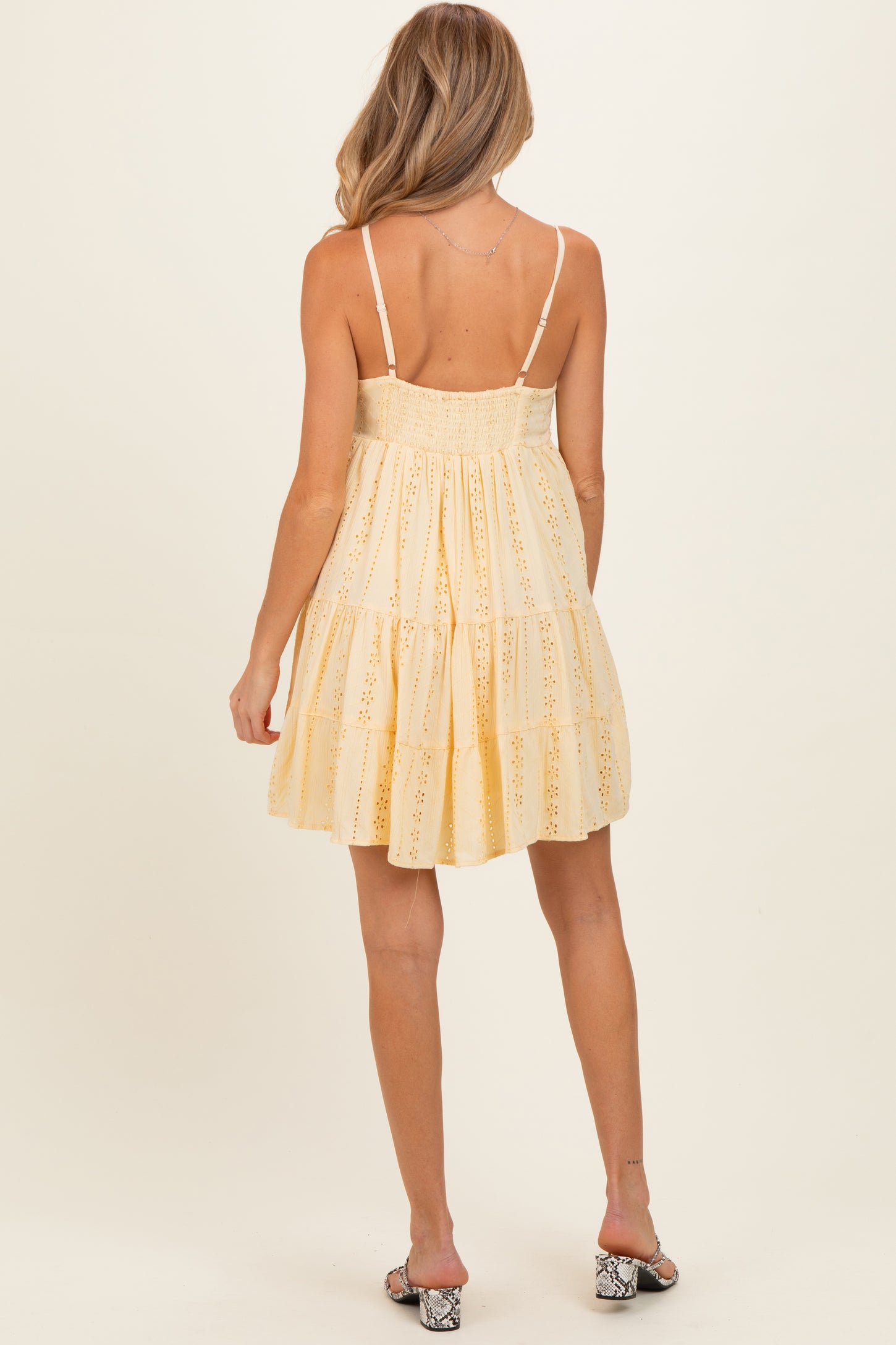 woman wearing a yellow tiered maternity dress with a smocked back and adjustable straps, showing a baby bump