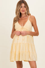 woman wearing a yellow maternity dress with adjustable straps and tiered design, showcasing a baby bump