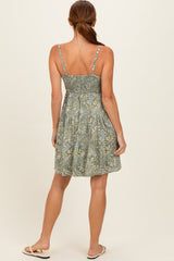 woman wearing a green floral print sundress with adjustable straps and a smocked back, showing the back view