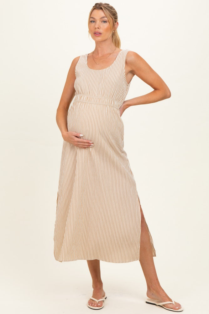 woman wearing a striped beige maternity maxi dress with a fitted waist and side slits, holding her baby bump