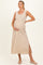 woman wearing a striped beige maternity maxi dress with a fitted waist and side slits, holding her baby bump