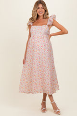 woman wearing a floral maternity maxi dress with puff sleeves and a fitted bodice, showcasing a baby bump