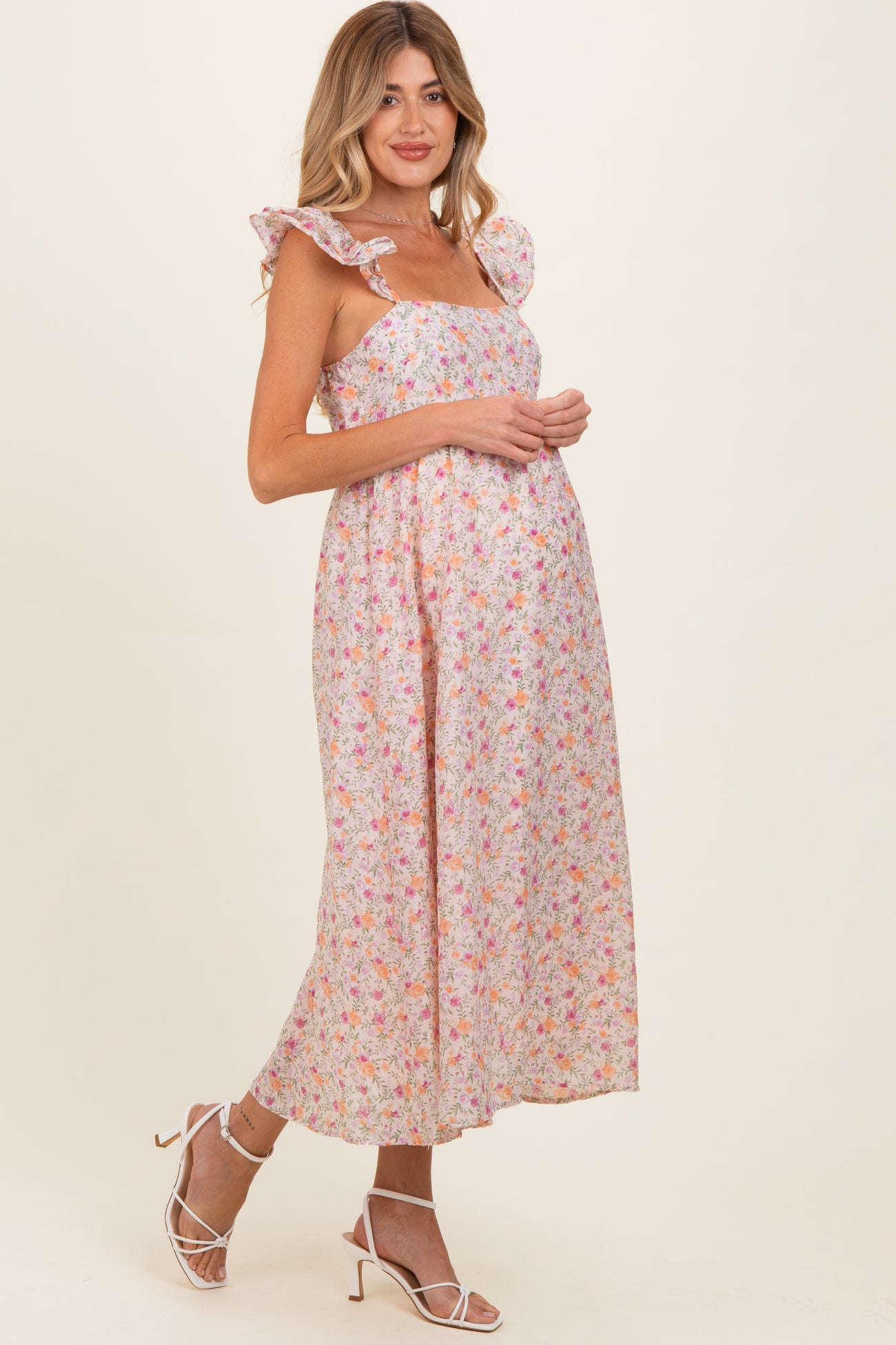 woman wearing a floral maternity dress with ruffle sleeves and a visible baby bump