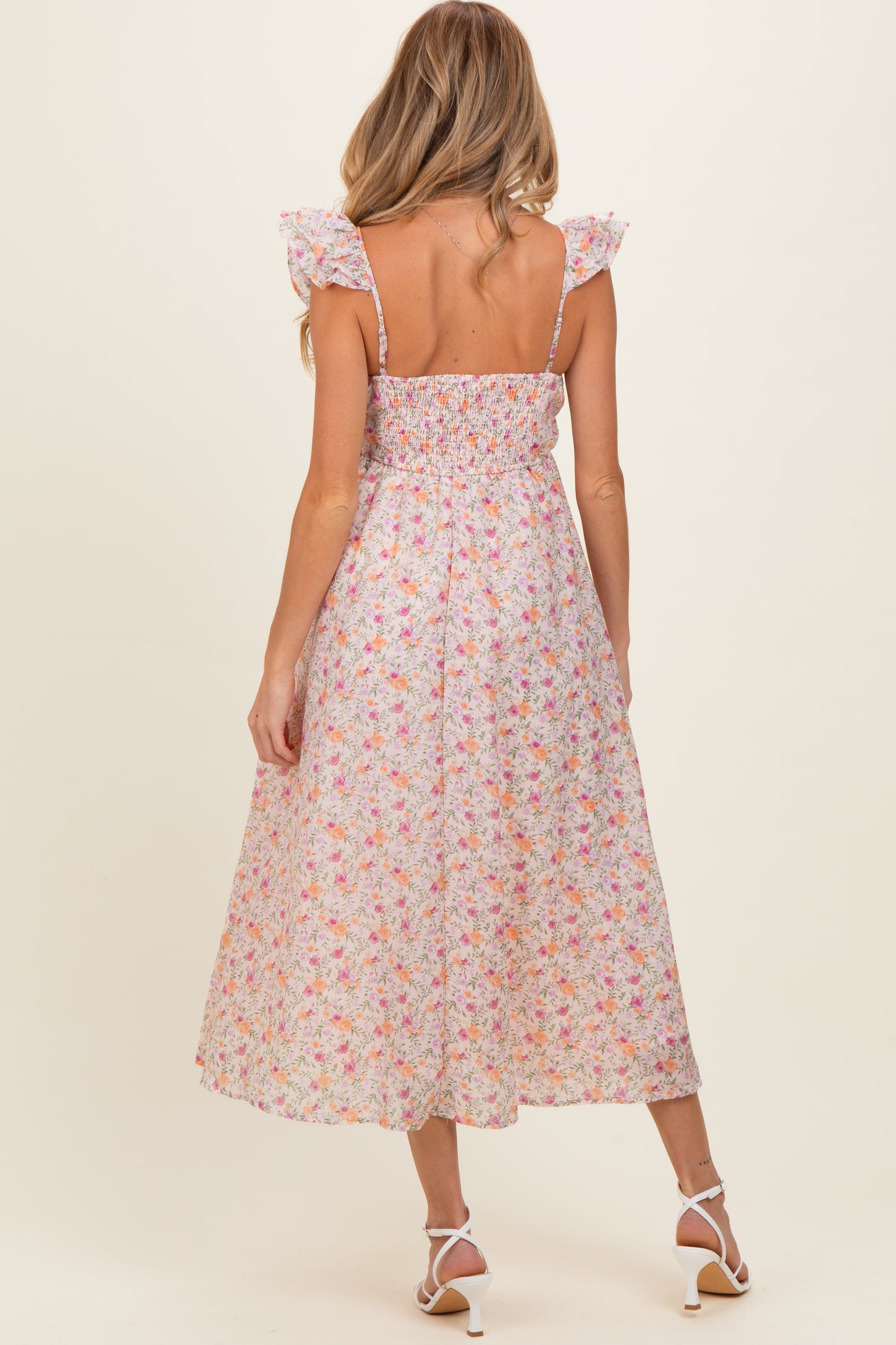 woman wearing a floral maternity dress with ruffled straps, shown from the back with a flowing midi length