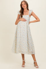 woman wearing a light floral print maternity dress with ruffled sleeves and her hands on her baby bump