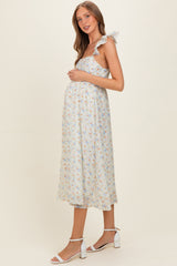 woman wearing a light blue floral maternity dress with ruffled straps, showcasing her baby bump