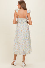 woman wearing a light floral print maternity dress with ruffled straps and a smocked bodice, showing her back