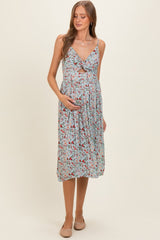 woman wearing a floral maternity dress with a fitted bodice and flowing skirt, holding her baby bump