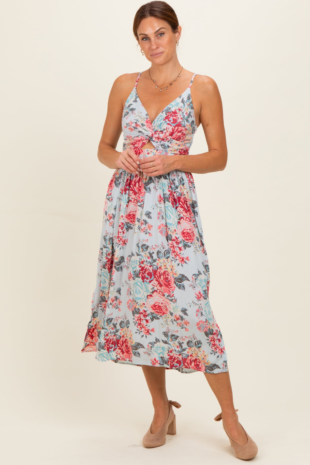 woman wearing a light blue floral midi dress with a knotted front and spaghetti straps