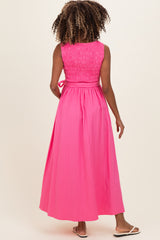 woman wearing a pink smocked back maternity maxi dress with a flowing skirt and sandals