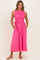 woman wearing a hot pink sleeveless dress with a smocked bodice and a tie waist, featuring side pockets