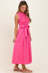 woman wearing a bright pink sleeveless maxi dress with a smocked bodice and a tie waist detail