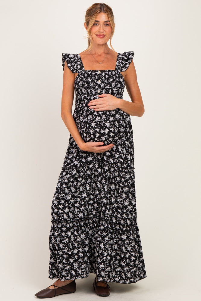 woman wearing a black floral maternity maxi dress and holding her baby bump