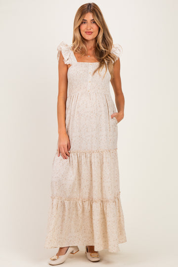 woman wearing a cream floral maternity maxi dress with ruffled straps and pockets, showing her baby bump