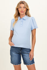 woman wearing a light blue maternity top with puff sleeves, paired with denim shorts and showing a baby bump