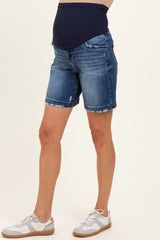 woman wearing a pair of dark blue maternity denim shorts with a stretchy belly band, styled with white sneakers