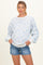 woman wearing a light blue floral patterned maternity sweatshirt with puff sleeves and denim shorts, showing her baby bump
