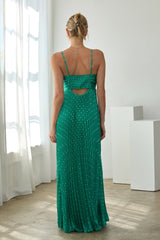woman wearing a green spaghetti strap maxi dress with a cutout back and pleated design