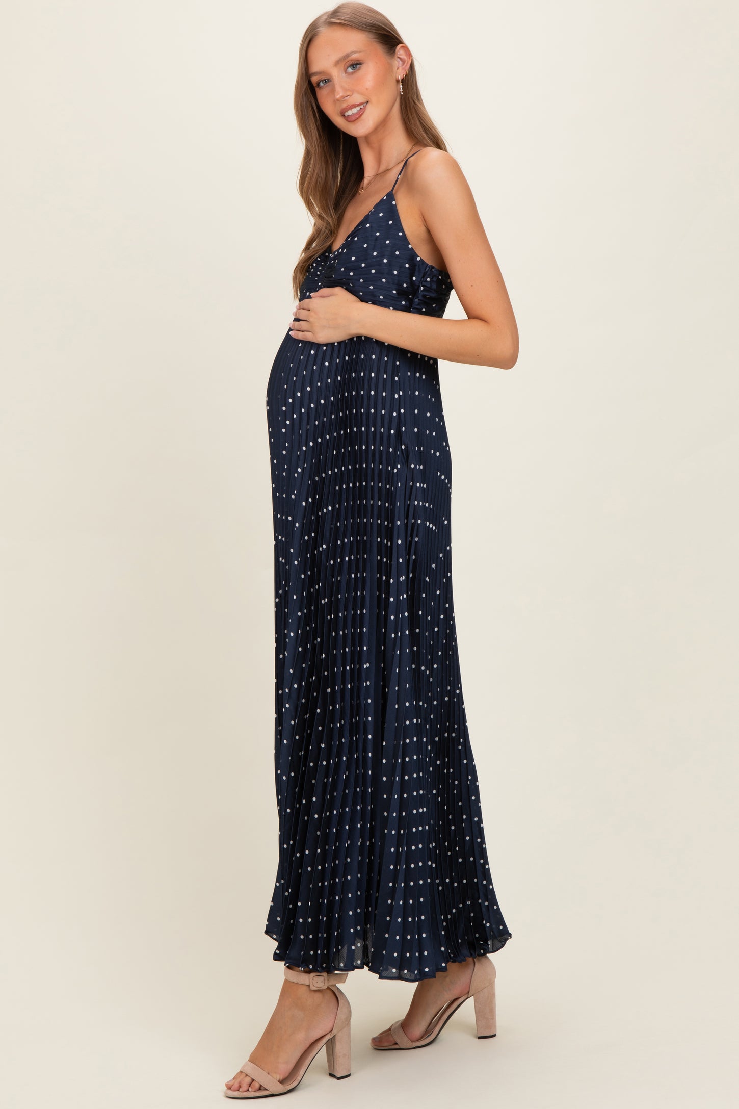 woman wearing a navy blue maternity maxi dress with white polka dots and a visible baby bump